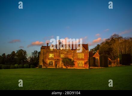 Vibrante luce del sole invernale sulla storica Chawton House di mattoni rossi del XVII secolo, a cui fa riferimento la romanziera Jane Austen con nuvole rosa e finestre luminose Foto Stock