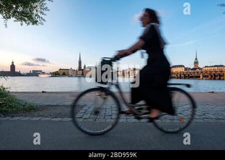 Donna in bicicletta sul lungomare di Stoccolma, Svezia, Europa Foto Stock