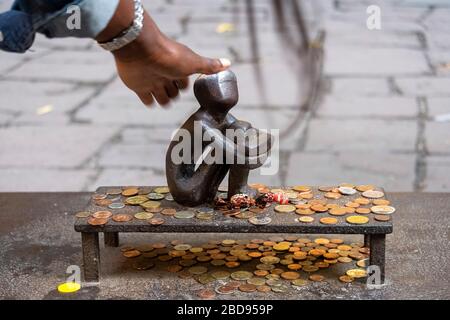 Turista che tocca la piccola scultura di Järnpojke o di Boy di ferro per fortuna a Stoccolma, Svezia, Europa Foto Stock