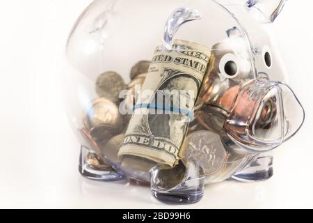 Piggy banca trasparente con la valuta americana isolata su sfondo bianco. Foto Stock