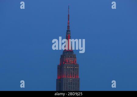 Weehawken, Stati Uniti. 7 aprile 2020. L'Empire state Building è visto illuminato in rosso in onore dei professionisti della sanità che lavorano per combattere il nuovo coronavirus COVID-19, e anche per celebrare la Giornata Mondiale della Sanità a New York negli Stati Uniti il Martedì notte, 07. Credit: Brazil Photo Press/Alamy Live News Foto Stock