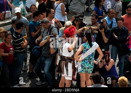 Turisti che scattano foto di una regina di bellezza che (erroneamente) presumono sia famosa con un uomo in costume su Piazza di Spagna, Roma, Italia, Europa, colore Foto Stock