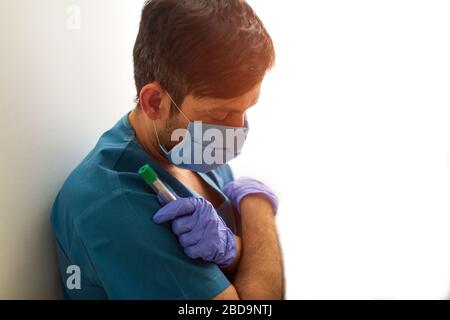 Assstent medico sovralavorato che dorme in laboratorio, campione provetta sangue in mano Foto Stock