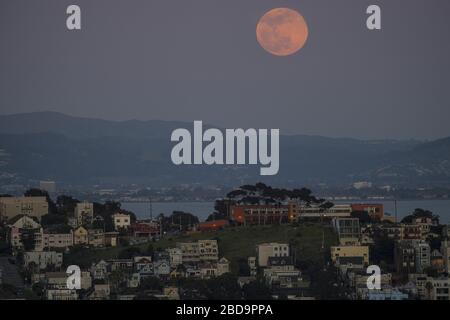 San Francisco, Stati Uniti. 7 aprile 2020. Una super luna rosa sorge attraverso la foschia dietro la collina di Poterero a San Francisco martedì 7 aprile 2020. La luna piena di aprile è la più vicina alla terra nel 2020. Foto di Terry Schmitt/UPI Credit: UPI/Alamy Live News Foto Stock