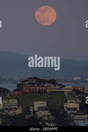 San Francisco, Stati Uniti. 7 aprile 2020. Una super luna rosa sorge attraverso la foschia dietro la collina di Poterero a San Francisco martedì 7 aprile 2020. La luna piena di aprile è la più vicina alla terra nel 2020. Foto di Terry Schmitt/UPI Credit: UPI/Alamy Live News Foto Stock