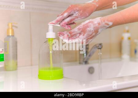 Lavando le mani con sapone sotto il rubinetto con acqua contro il nuovo coronavirus. Antisettico, igiene, concetto sanitario. Donna lava le mani con li Foto Stock