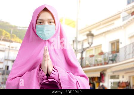 Donna musulmana asiatica in un velo e indossare maschera influenzale pregare. Prevenire la malattia influenzale diffusa Coronavirus Foto Stock