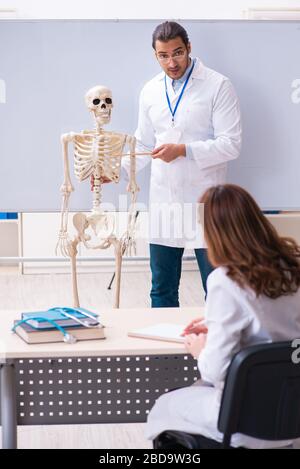 Giovane insegnante di sesso maschile medico, scheletro e studentessa in classe Foto Stock