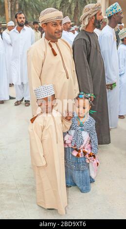 Un orgoglioso padre di Omani con i suoi due figli piccoli, tutti vestiti in modo immacolato con abiti tradizionali, a Muscat nel Sultanato dell'Oman. Foto Stock