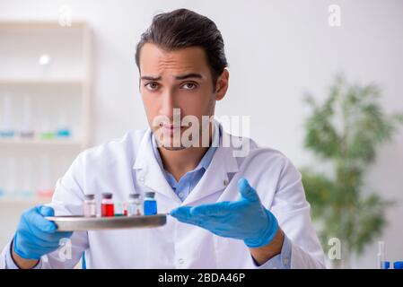 Giovane assistente di laboratorio maschile nel concetto di sintesi del farmaco Foto Stock