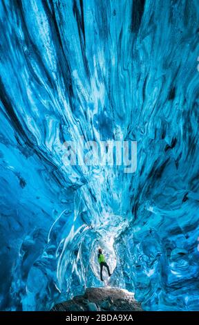 L'uomo osserva in una grotta di ghiaccio di Breidamerkurjokull, Austurland, Islanda, Europa del Nord Foto Stock