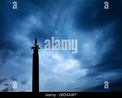 Silhouette della statua con guerriero su Leopard è indipendenza monumento sulla piazza della Repubblica di Almaty in Kazakistan a cielo nuvoloso scuro dello sfondo Foto Stock