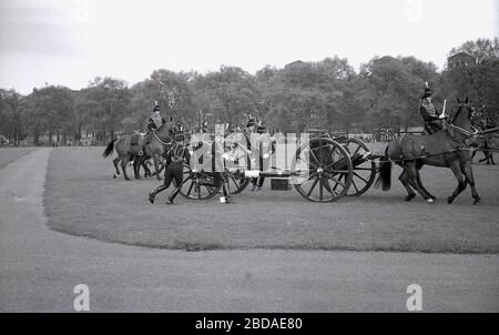 Anni '60, storico, cavalieri cavalli che sposta le armi in posizione per una Royal Gun Salute al Green Park vicino a Buckingham Palace, Westminster, Londra, Inghilterra. I saluti delle armi segnano occasioni speciali reali, tra cui il compleanno della Regina, e sono una mostra tradizionale di pageantry britannico. Foto Stock