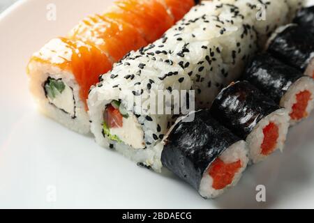 Deliziosi panini di sushi sullo sfondo bianco della ciotola, primo piano. Cucina giapponese Foto Stock