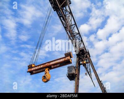 Gru a cavalletto arrugginita da 50 tonnellate. Vecchia gru abbandonata su uno sfondo di cielo blu. Fabbrica fallita a causa della crisi globale. Calo della produzione. Foto Stock