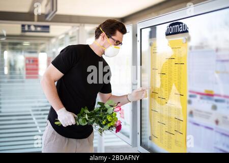 Un uomo raccoglie qualcuno alla stazione ferroviaria in un'era del virus corona con una maschera respiratoria e guanti di gomma Foto Stock