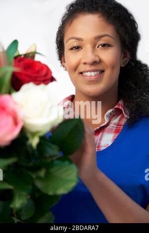 Ritratto di femmina disponendo di fiorista bouquet di Lillies e rose contro uno sfondo bianco Foto Stock