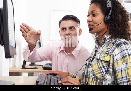 Formazione per uomini d'affari - dipendente femminile che indossa le cuffie nell'ufficio del call center Foto Stock