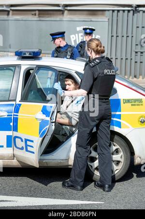 Una pattuglia di polizia con gli agenti di supporto della Comunità negozia con un uomo e lo ha messo in un'automobile di pattuglia a Weston-super-Mare durante il blocco di Coronavirus Foto Stock