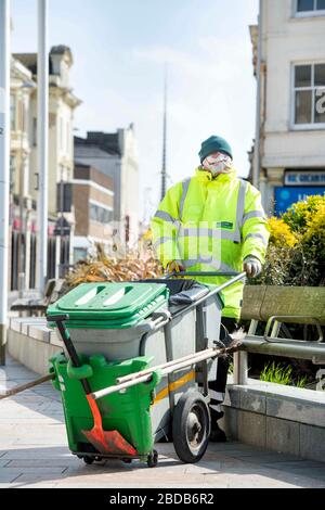 Un pulitore di strada con maschera facciale improvvisata a Weston-super-Mare durante il blocco Coronavirus UK Foto Stock