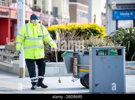 Un pulitore di strada con maschera facciale improvvisata a Weston-super-Mare durante il blocco Coronavirus UK Foto Stock