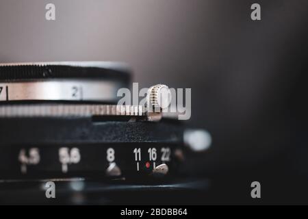 Immagine macro e bassa profondità di campo (messa a fuoco selettiva) con i contrassegni sull'obiettivo di una fotocamera a soffietto molto vecchia (tempo di esposizione e f-stop). Foto Stock