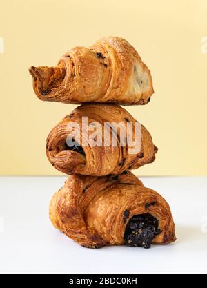 composizione di tre croissant con vetrino ripiegato di cioccolato su fondo giallo Foto Stock