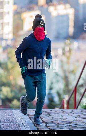 ragazzo che corre al piano superiore con maschera chirurgica fatta in casa Foto Stock