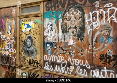 Parte anteriore in legno coperta in una miscellanea di Street art, graffiti, etichette e adesivi. Rue des Cinq Diamants, Butte aux Cailles, Parigi. Foto Stock