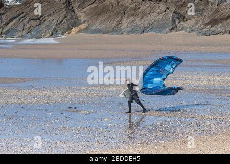 Un surfista kite boarder che lotta per portare il suo kite surf attrezzature in alto vento su Fistral Beach a Newquay in Cornovaglia. Foto Stock