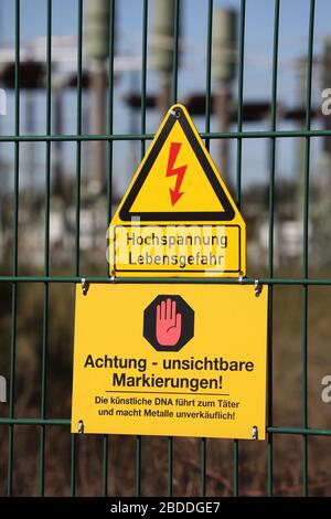 22.03.2020, Nunsdorf, Brandeburgo, Germania - segni - DNA artificiale - e - pericolo di alta tensione per la vita - presso la recinzione di una stazione di trasformazione. 00S20 Foto Stock