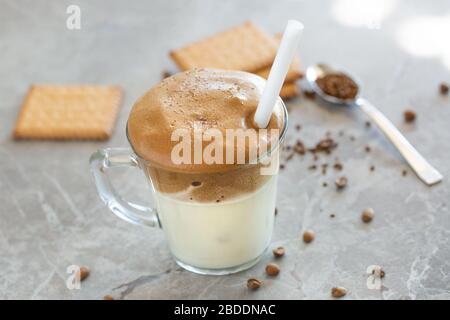 Crema di caffè Dalgona con latte in tazza di vetro con cucchiaio sullo sfondo Foto Stock