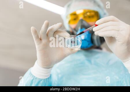 Vista dal basso di un ricercatore in laboratorio che gocciola un campione di sangue in una piastra Petri. Concetto di creazione di vaccini. Foto Stock