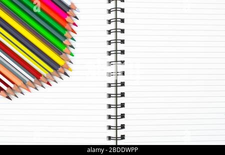 Pastelli a matita di colore diverso messi in una fila di forma ondulata prima di un diario bianco Foto Stock