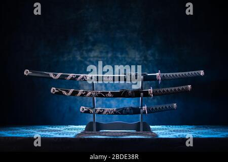 Katana, wakizashi e tango in piedi, con una drammatica luce blu Foto Stock