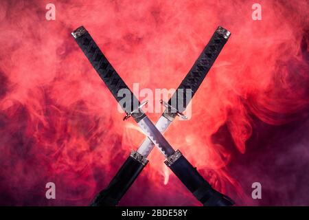 Lame parzialmente trafilate di due katanas in fumo rosso Foto Stock