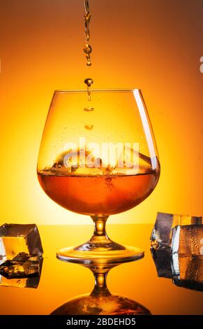 Un grande bicchiere di whisky con spray è stato fotografato su vetro nero con riflessione Foto Stock