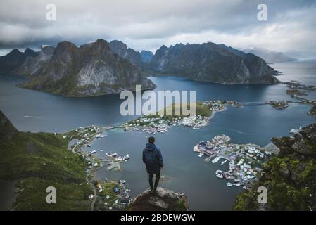 Norvegia, Isole Lofoten, Reine, uomo guardando il fiordo fromÂ ReinebringenÂ montagna Foto Stock