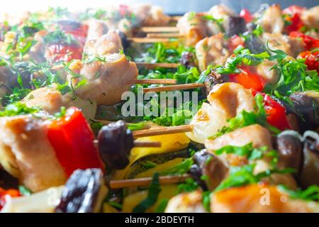 Fettine di pollo, melanzane, pomodoro, peperoni dolci e funghi sono strung su spiedini di legno e fritti fino a rosato. Deliziosa prelibatezza con fresco ch Foto Stock