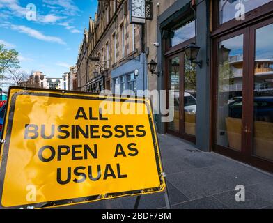 Leith, Edimburgo, Scozia, Regno Unito. 8 Aprile 2020. Covid-19 Lockdown: Un cartello 'Business Open as usual' posto durante i tram per Newhaven lavori stradali è ora fuori posto, come tutti i ristoranti e bar normalmente occupati sulla Shore sono chiusi a causa della pandemia Foto Stock