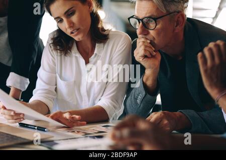 Uomini d'affari che guardano le foto e discutono del disegno della rivista. Gruppo di affari creativo che discute il disegno della rivista. Foto Stock