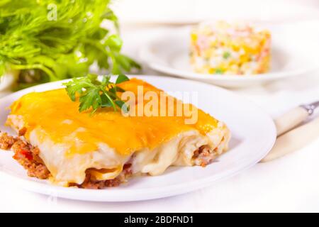 Cannelloni italiani al forno con carne tritata e salsa di bechamel sul piatto bianco Foto Stock