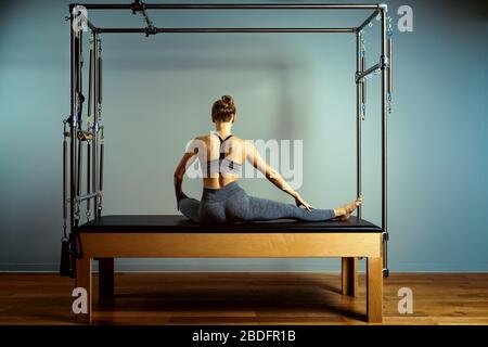 allenamento dei pilates di leotard. esercizi di riforming dei pilates di atletica. attrezzature della macchina dei pilates di pilates. sport di stiramento della giovane donna in letto di reforming Foto Stock