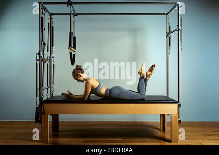 allenamento dei pilates di leotard. esercizi di riforming dei pilates di atletica. attrezzature della macchina dei pilates di pilates. sport di stiramento della giovane donna in letto di reforming Foto Stock