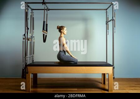 allenamento dei pilates di leotard. esercizi di riforming dei pilates di atletica. attrezzature della macchina dei pilates di pilates. sport di stiramento della giovane donna in letto di reforming Foto Stock