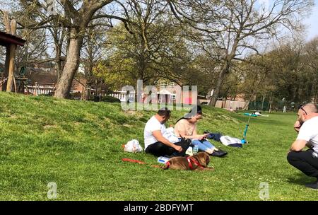 High Wycombe, Regno Unito. 8 aprile 2020. I bambini giocano in una zona 'la polizia 'nastro fuori mentre il lato del genitore prende il sole mentre ignorano le linee guida del governo durante la Pandemia di Covid-19 in cui il governo ha dato le regole rigorose soltanto su lasciare la sede per il lavoro essenziale, lo shopping dell'alimento e una forma di esercitazione al giorno. Il Rye Park in High Wycombe, Bucks il 8 aprile 2020. Foto di Andy Rowland. Credito: Prime Media Images/Alamy Live News Foto Stock