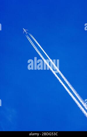 Jet aereo contrasta le nuvole alte nell'atmosfera. Bel cielo blu che mette in risalto i contrails Foto Stock