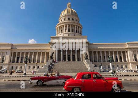 HAVANA, CUBA - 10 DICEMBRE 2019: Le auto classiche americane dai colori vivaci che servono da taxi passano sulla strada principale di fronte all'edificio Capitolio i Foto Stock