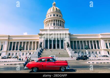 HAVANA, CUBA - 10 DICEMBRE 2019: Le auto classiche americane dai colori vivaci che servono da taxi passano sulla strada principale di fronte all'edificio Capitolio i Foto Stock