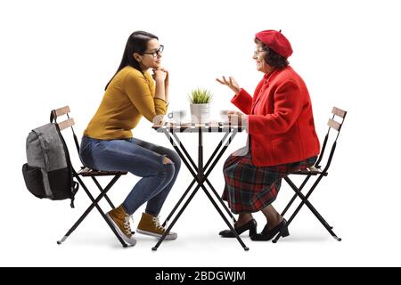 Foto di profilo a tutta lunghezza di una giovane e senior seduta in un bar e parlare isolato su sfondo bianco Foto Stock